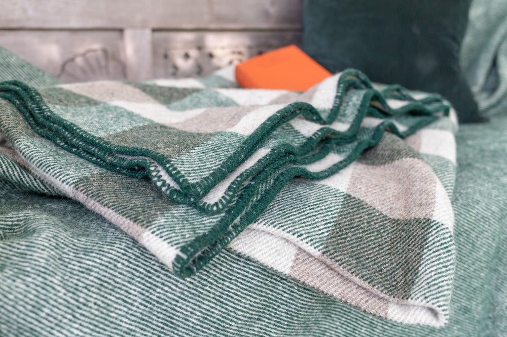 Topsy Farms' green and grey Canadian wool blanket on a bed