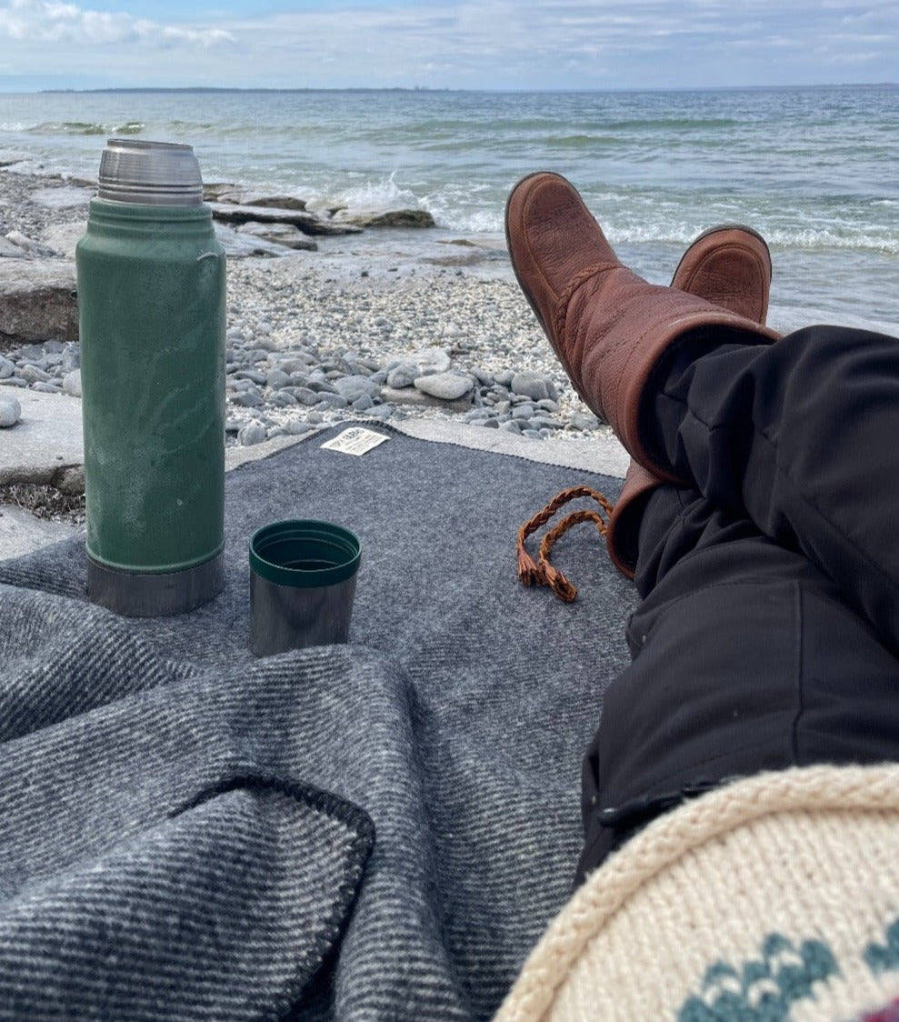 Topsy Farms' charcoal wool throw blanket on a beach