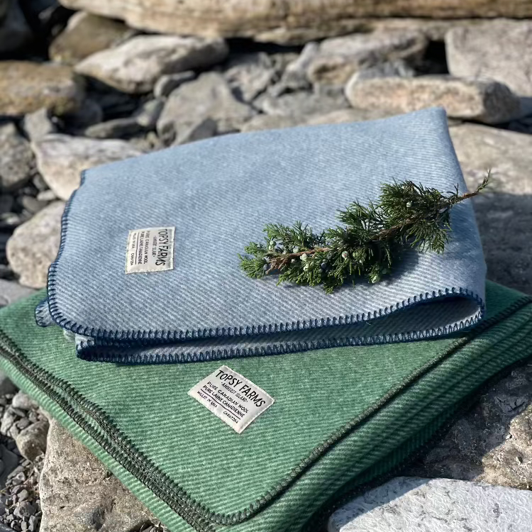 Topsy Farms' Canadian wool throws in blue and green on a rocky beach
