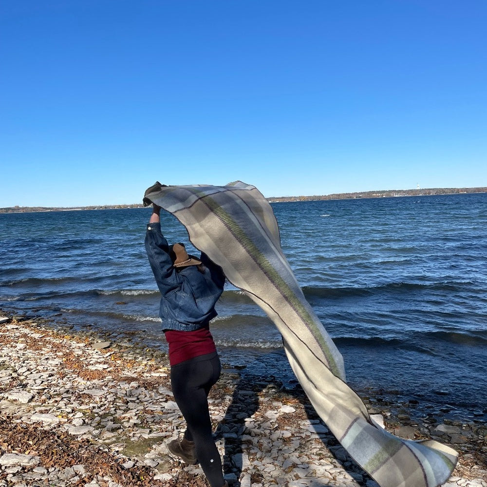 Woman walking on the beach with a Topsy Farms' Shoreline patio wrap flowing behind her