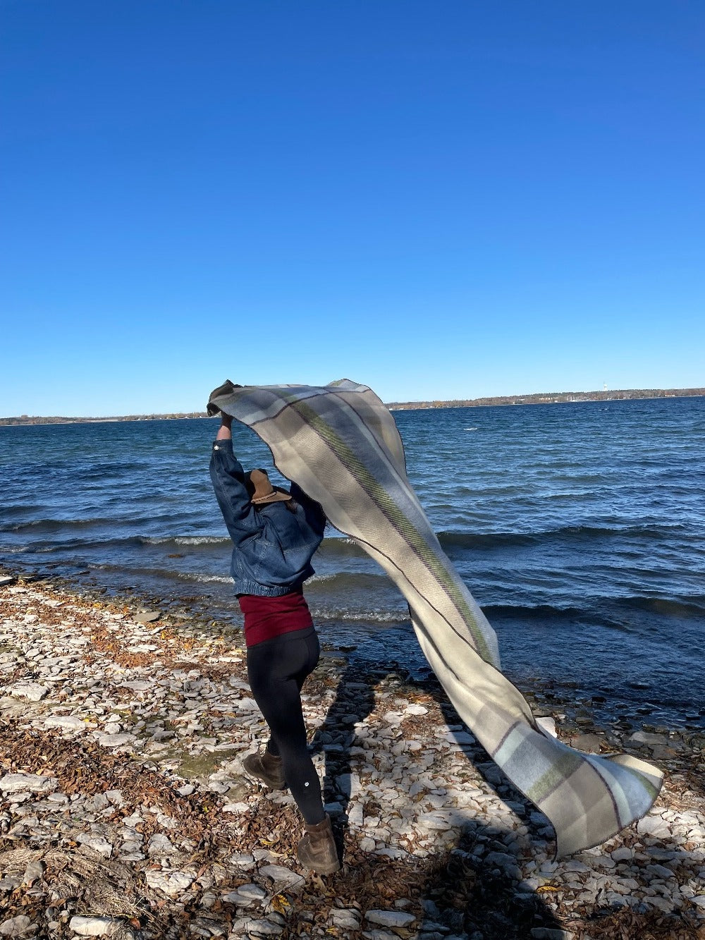 Woman walking on the beach with a Topsy Farms' Shoreline patio wrap flowing behind her