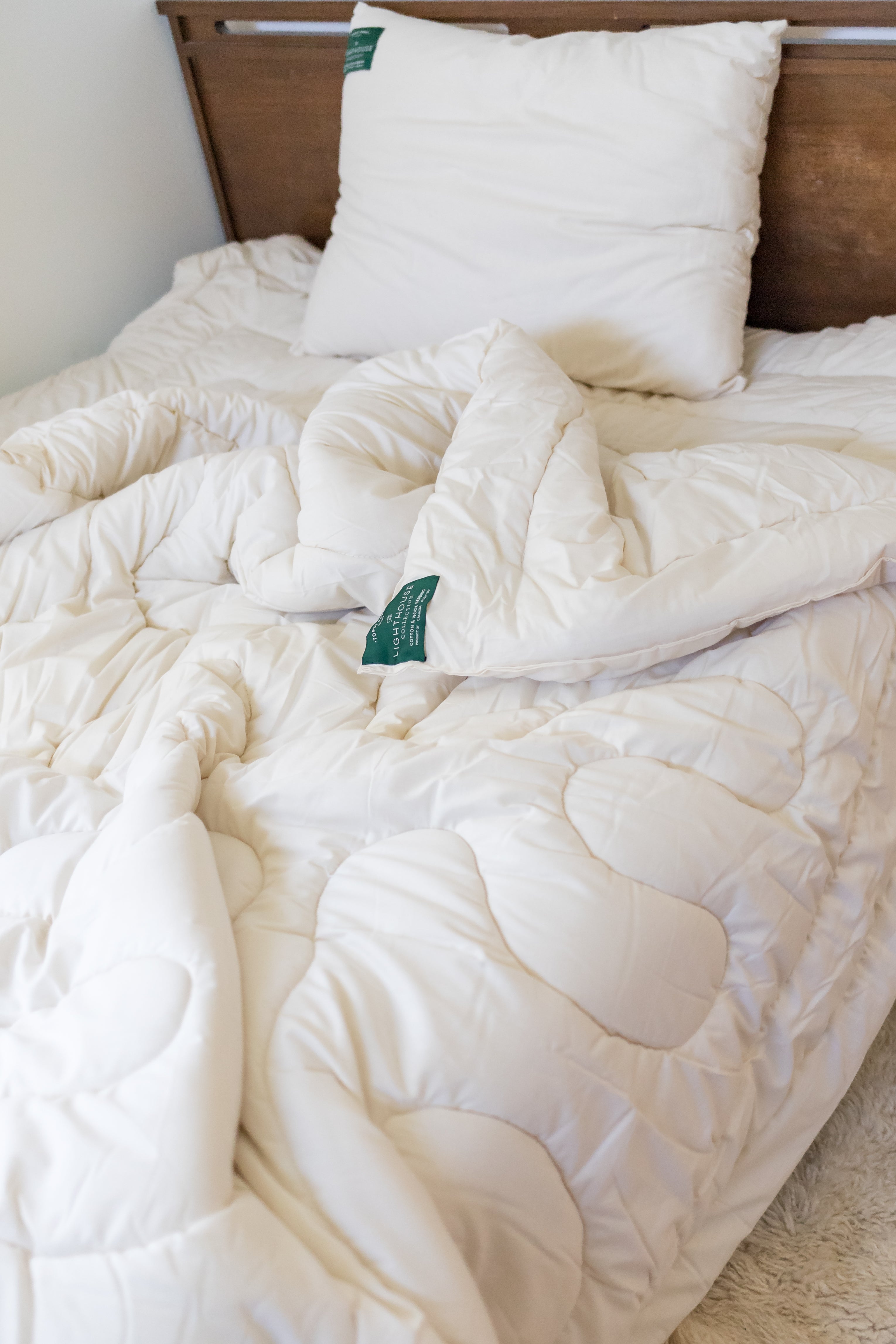 Topsy Farms' wool filled pillows and duvet on a brown bed, with a turquoise wool blanket on top