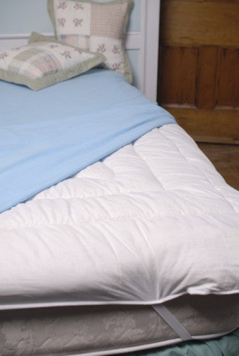 Topsy Farms' wool filled pillows and duvet on a brown bed, with a turquoise wool blanket on top