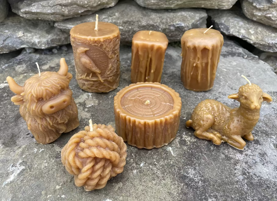 Topsy Farms' handmade beeswax candles on a stone wall