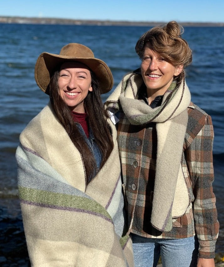 Two women standing by a lake, wearing Topsy Farms' Shoreline wrap and scarf