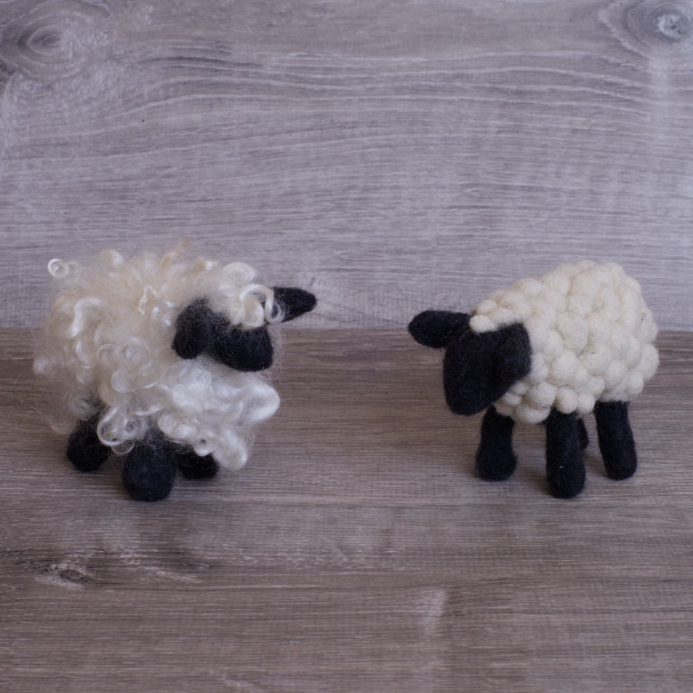 two small felted sheep, both white with black legs and face