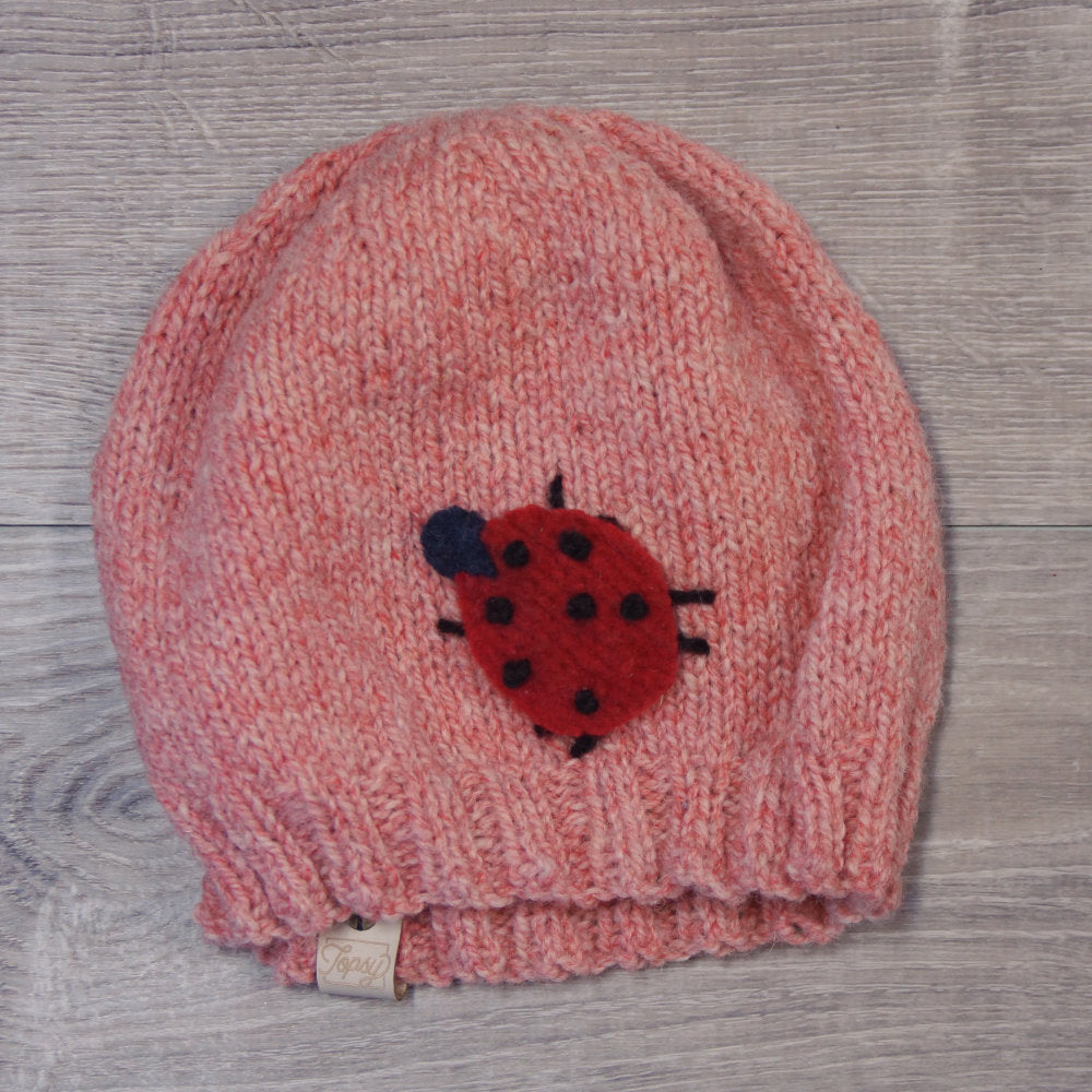 Light pink knitted toque with felted ladybug attached. Made with Topsy Farms' wool