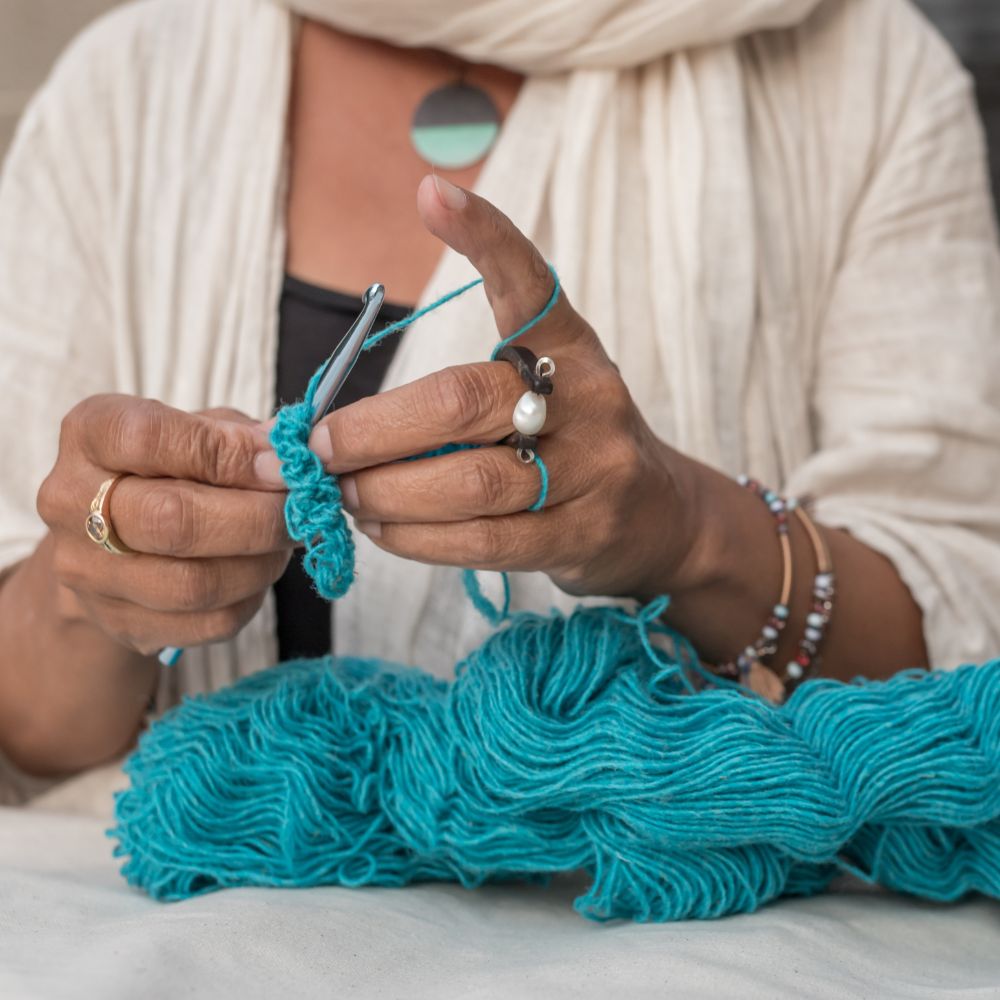 Brown woman crocheting with Topsy Farms' Canadian wool yarn