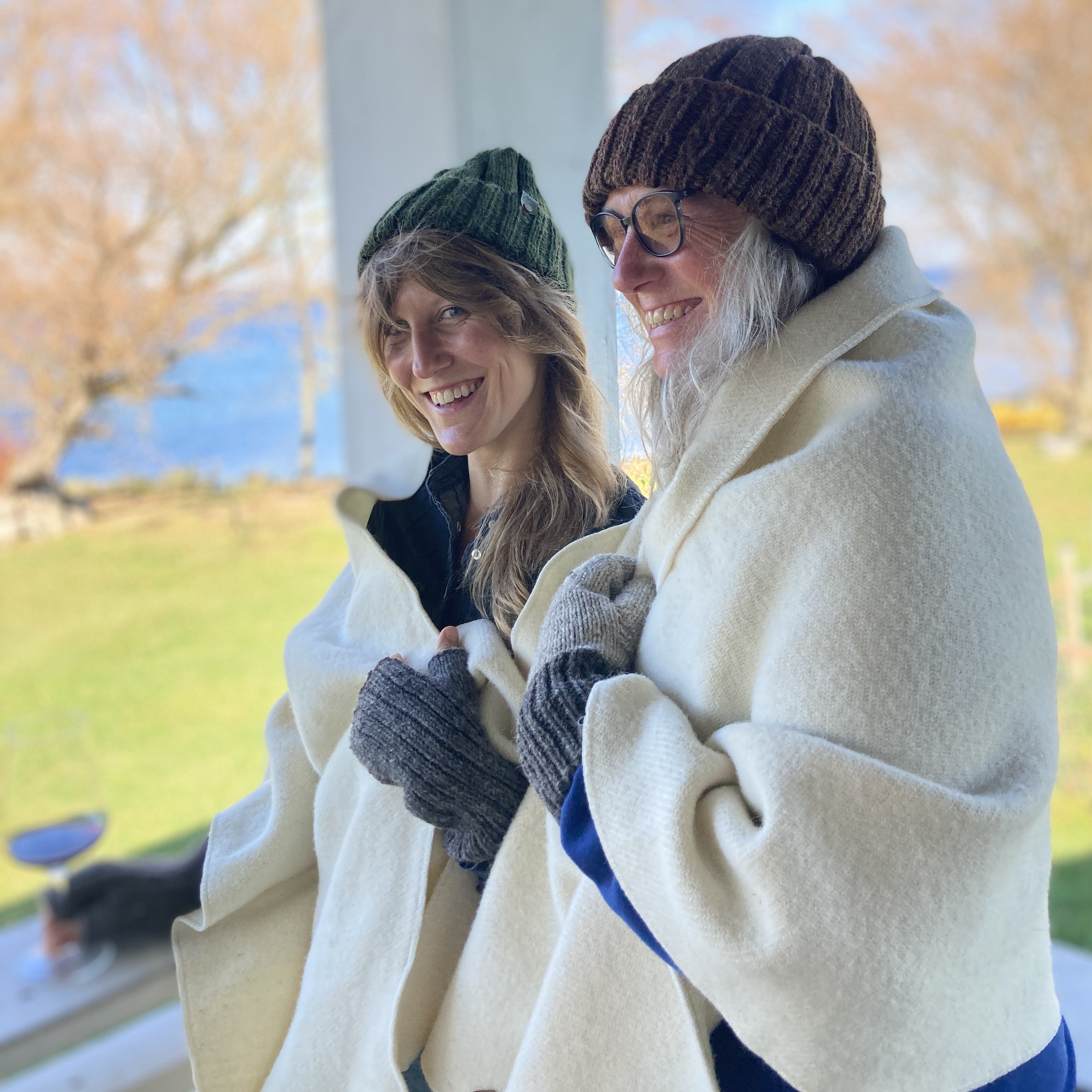 Two women in wool hats and Topsy Farms' wool patio wraps standing on a deck