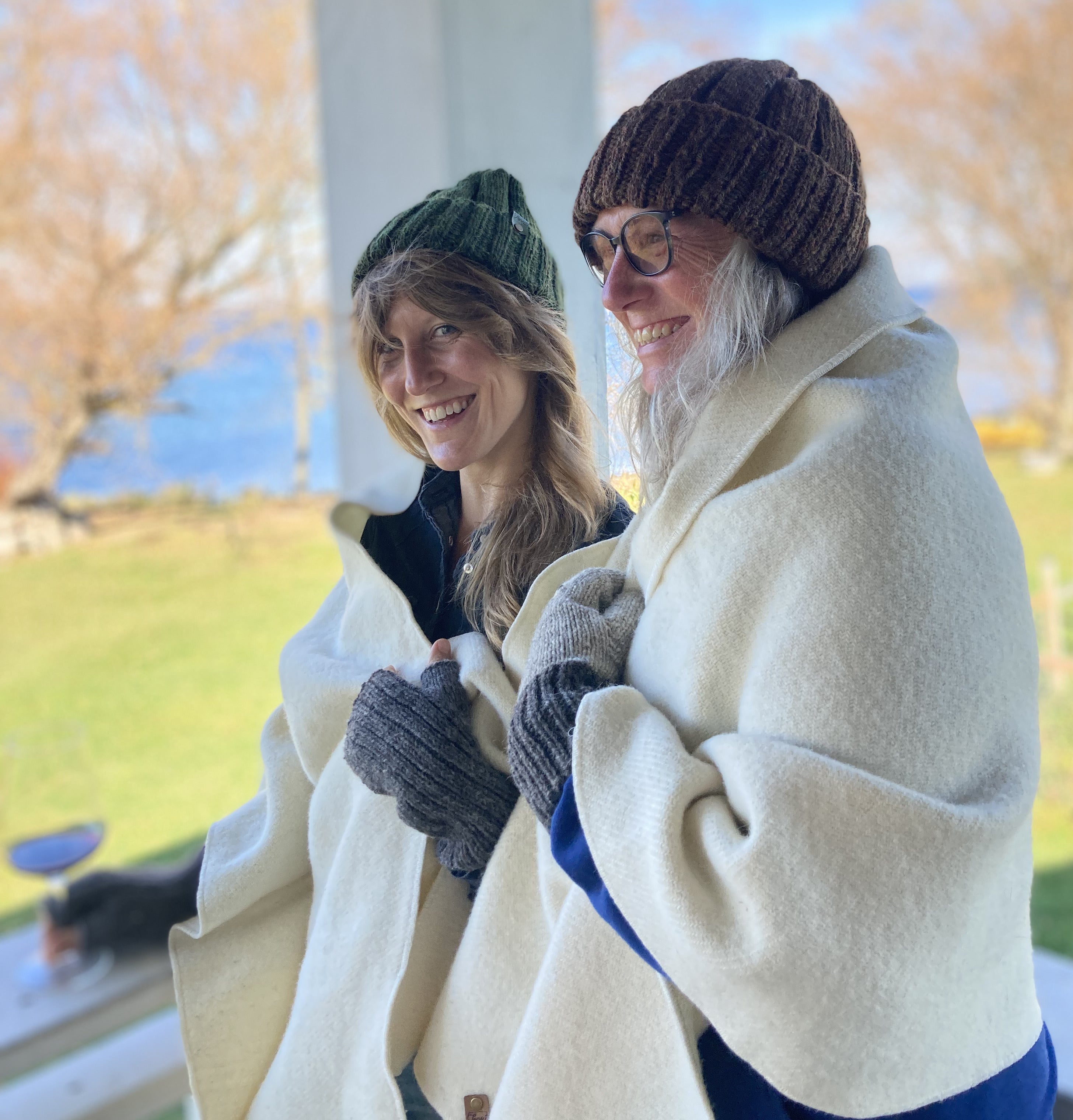 Two women in wool hats and Topsy Farms' wool patio wraps standing on a deck